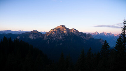 Fototapeta na wymiar Berge bei Sonnenaufgang mit Bäumen im Vordergrund