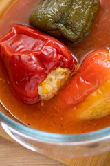 Peppers stuffed with meat in a glass bowl on a wooden table