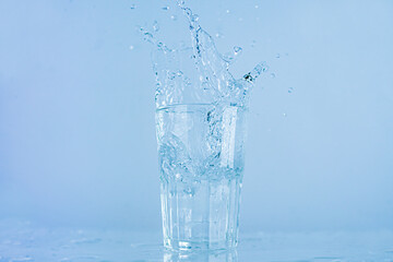 Naklejka na ściany i meble A glass of water splashed up. The water rose from a clear glass with a square.