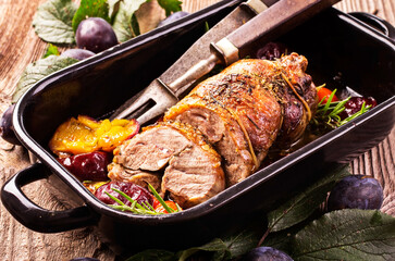 Traditional French barbecue lamb roast with vegetable and plums served as close-up in a rustic casserole