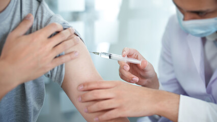 General practitioner or doctor vaccinating old patient in clinic..