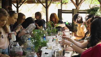 Person making terrarium. Group of people at outdoor florarium training and seminar. Self-sustaining micro garden ecosystem. People learning to create terrariums. Zen meditation hobby. Creative meetup.