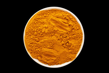 Aromatic turmeric spice in white ceramic dish on black background, close-up, top view.