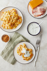 Snack waffles with bacon, cheddar cheese and dried fried onions and tzatziki sauce on light background