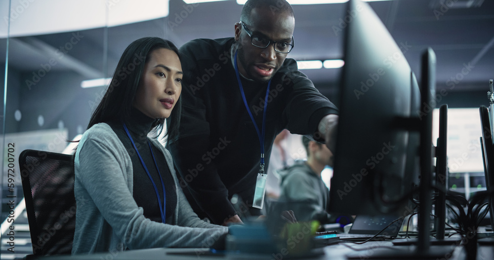 Fototapete Two Diverse Multiethnic Colleagues Having a Conversation While Busy Working on a Team Project. Asian Female Designer Talking with an African Project Manager. Teamwork in Technology Laboratory