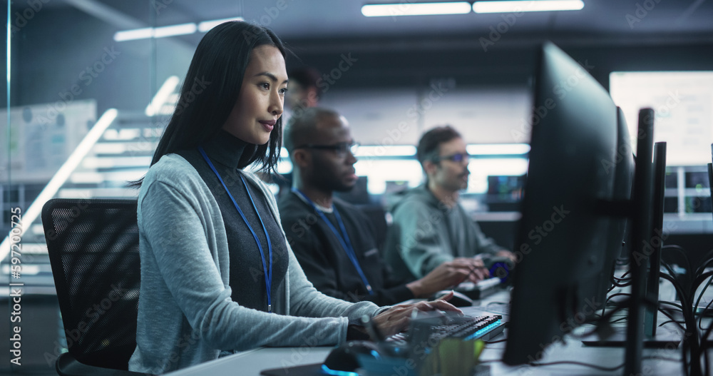 Poster young asian female software developer working on computer together with diverse creative colleagues.