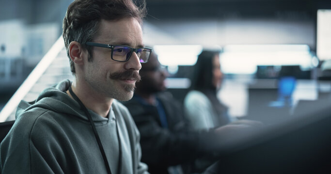 Portrait of a Happy Mustachioed Computer Science Team Member Working on a Computer in a Research and Development Technological Center Facility. Smiling Man Writing Code for Industrial Software