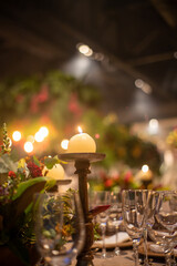 Party Rounded candle some plants and glasses with blurred backgorund 
