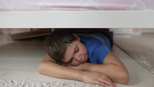 Boy lies under a bed