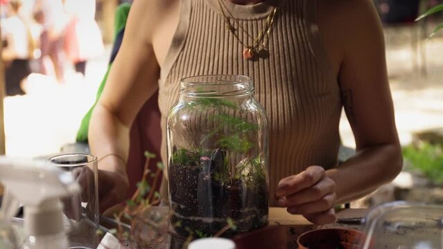 Person making terrarium. Group of people at outdoor florarium training and seminar. Self-sustaining micro garden ecosystem. People learning to create terrariums. Zen meditation hobby. Creative meetup.