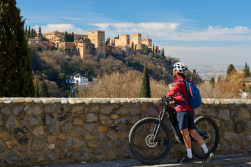 nice active senior woman cycling with her electric mountain bike in Granada below the world...