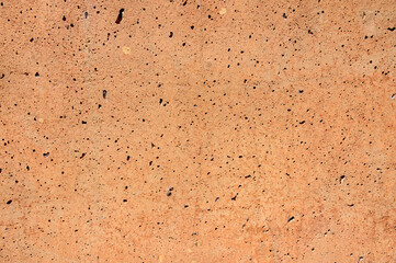 Stunning light red concrete background with numerous small holes and flaws