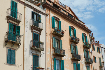 Fototapeta na wymiar Facade of a vintage buildings downtown Bosa, Sardinia, Italy. Shutters on the windows, Italian aesthetics