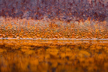 Macro close up of an old forgotten water filled rusty iron barrel with colorful corrosion belwo and...