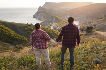 Tourists: a guy and a girl on top of a mountain watching a beautiful sunset. Travel and active life concept.