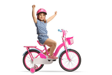 Child with a helmet riding a pink bicycle with training wheels and gesturing happiness