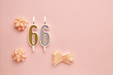 Candles with the number 66 on a pastel pink background with festive decor. Happy birthday candles. The concept of celebrating a birthday, anniversary, important date, holiday. Copy space. banner