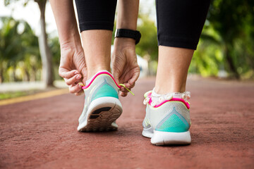 Fototapeta na wymiar Runner woman tying up laces of shoes, getting ready to run for cardio and weight loss