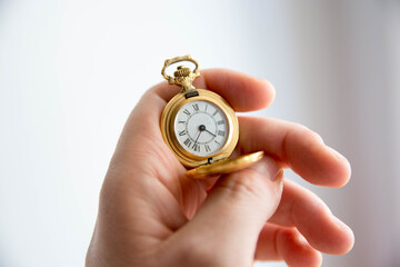 Mano sosteniendo reloj de bolsillo antiguo. Dorado. Copy space. Concepto tiempo.