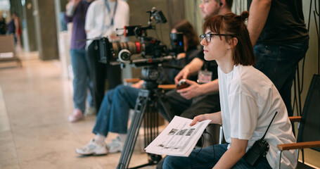 The director is a woman at work on the set. The director works with a group or with a playback...