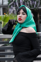 A brunette woman and red lips in a black dress, a bright scarf on her head. close-up portrait