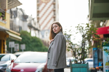 Obraz premium A beautiful young girl is standing on a city street in casual clothes, waiting.