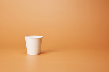Disposable white single one recyclable cardboard paper cup isolated on the bright solid fond plain...