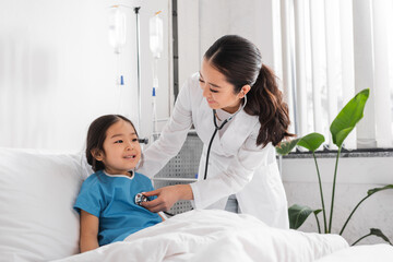 young asian doctor with stethoscope examining joyful girl in pediatric hospital. - Powered by Adobe