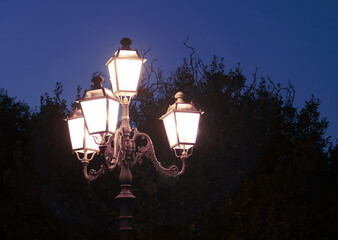 Farola de estilo clásico iluminada en Castro, Italia. Silueta de la estructura de la farola y de...