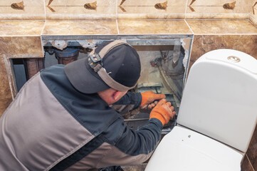 Handyman fixing a water pipe. Plumbing repair in a broken wall of a house.