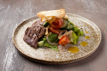 Fried slices of meat and salad in a plate on a brown background.