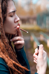 young pretty girl teenage with dreadlocks outside smoking cigarette, looking like real junky, social issues concept.