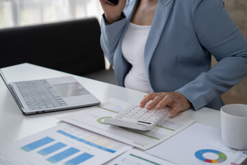 Professional Asian senior female accountant using calculator, calculating sales accounts.