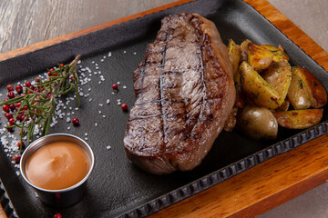 Steak and potatoes in a plate on a brown background.