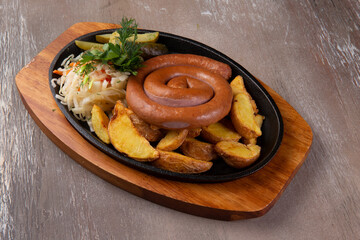 Sausages and potatoes in a plate on a brown background.