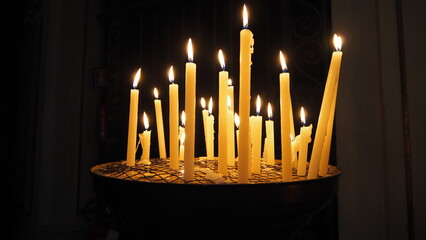 Varias velas pequeñas encendidas con fondo negro.