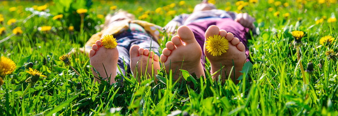 Child feet on the grass in the spring dandelions garden. Selective focus.