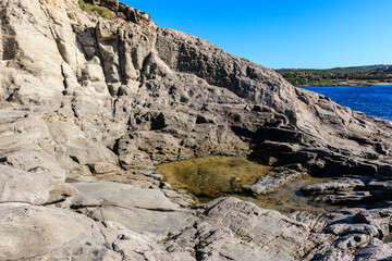 unusual rock formations of the volcanic cliff on Cala Sapone beach, quartz-trachitic ignimbrites.