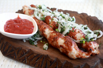 Chicken lula kebab with onions on board