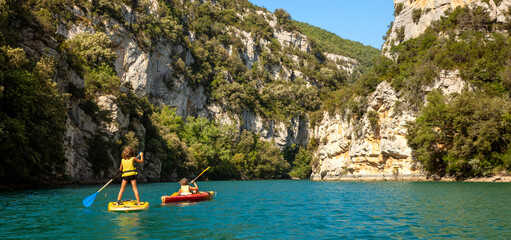 Two brothers enjoying water sport- paddle and kayak on the lake- France, Verdon