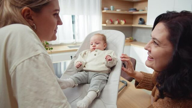 The grandmother and mother engage in a casual conversation while tending to child. Love, wisdom, and nurturing heart of familial relationships. Deep connection and joy.