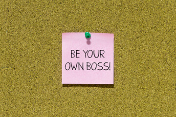 Be your own boss text on pink post-it paper pinned on bulletin cork board. This message can be used...
