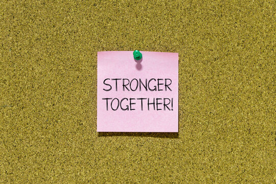 Stronger together text on pink post-it paper pinned on bulletin cork board. This message can be used in business concept about stronger together.