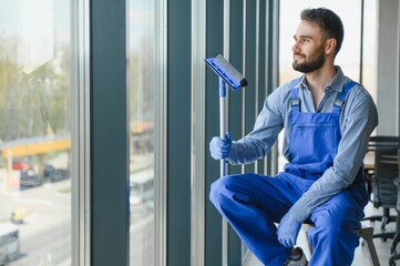 Fototapeta premium Male janitor cleaning window in office