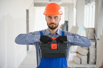 Portrait of young and hardworking constructor posing in big unfinished room. Building concept