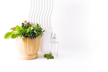 Wooden mortar with plants and organic herbal skin care cosmetic products on white background close up. Alternative medicine and cosmetology concept.