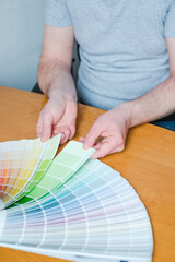 Man choosing paint color for home interior design project sitting at the table. top view