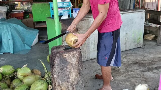 The coconut worker is peeling green coconuts deftly