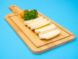 Sliced Halloumi cheese with herbs and tomatoes on a wooden board as a concept of Cypriot products