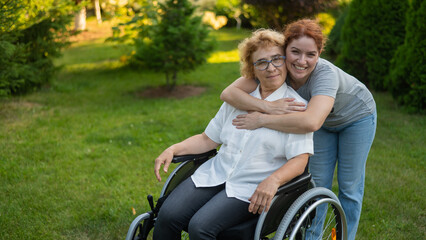 Obraz premium Caucasian woman hugging an elderly mother sitting in a wheelchair. Walk outdoors. 